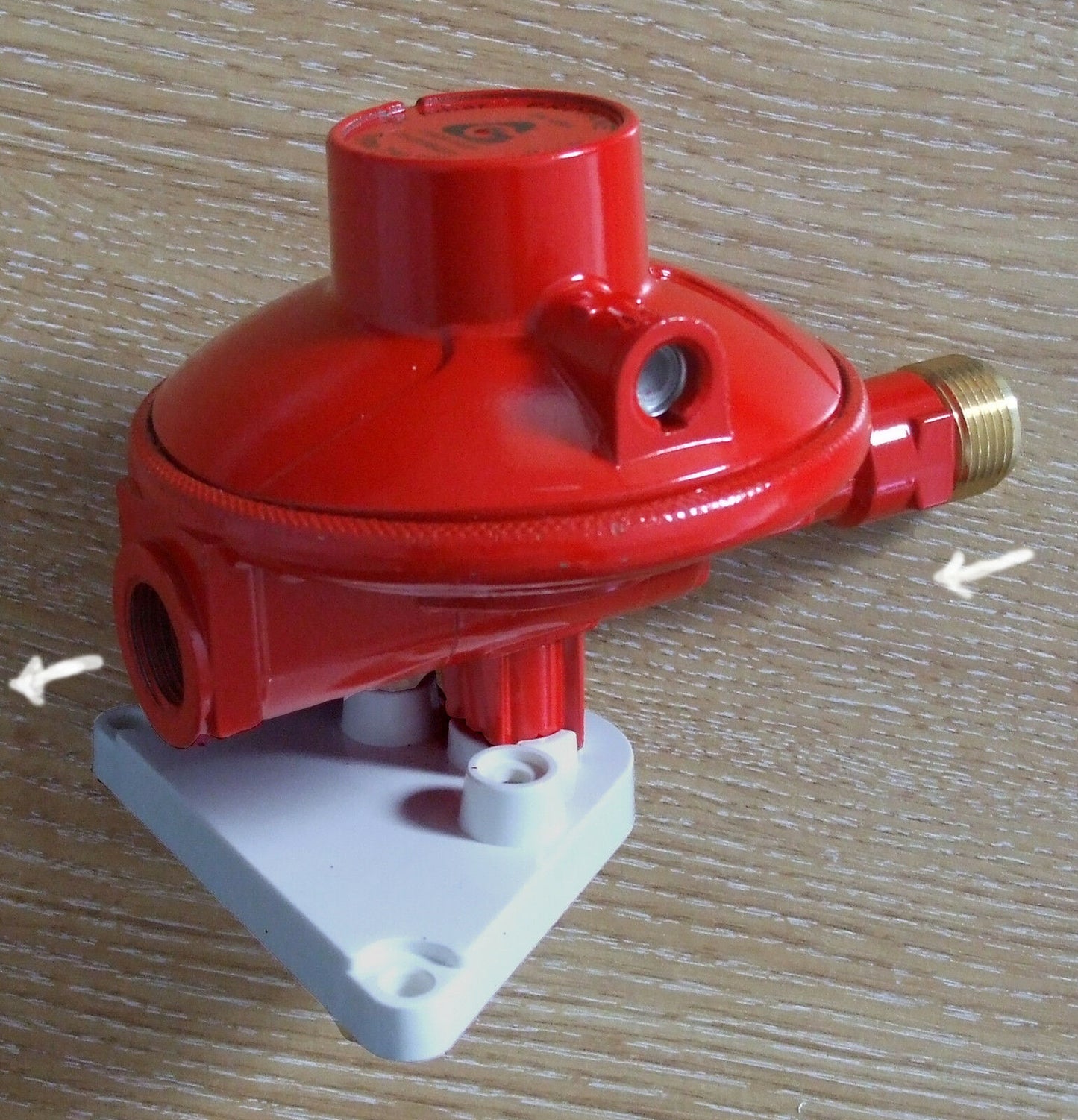 red propane gas regulator with wall mount attached.